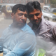 A man sprays two men on a motorcycle in Karachi.
